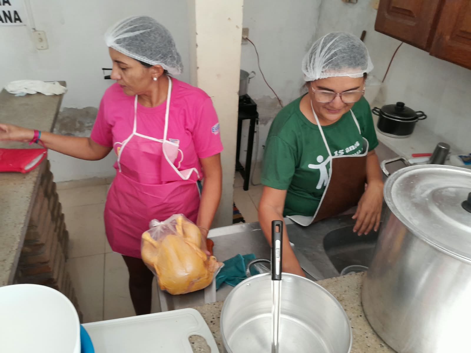 Trabalho em dupla na cozinha do projeto, em dia de produção.